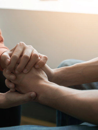 A person holds the hand of another person as a sign of support.